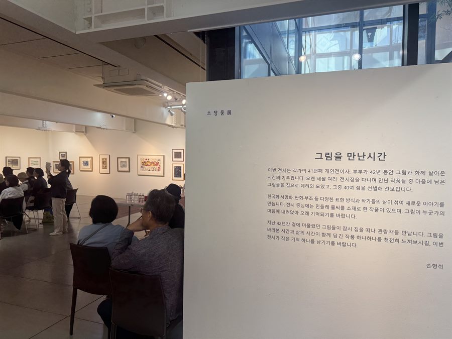 서문 판넬 앞에 앉은 손님들과 그 너머의 전시 벽면